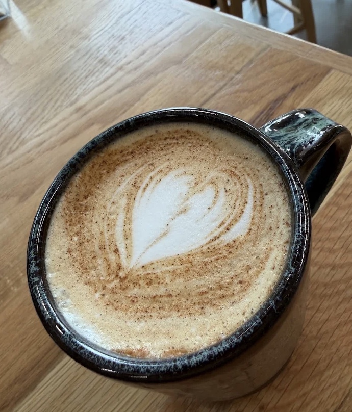 A latte with heart-shaped latte art in a Grindstone Coffee mug